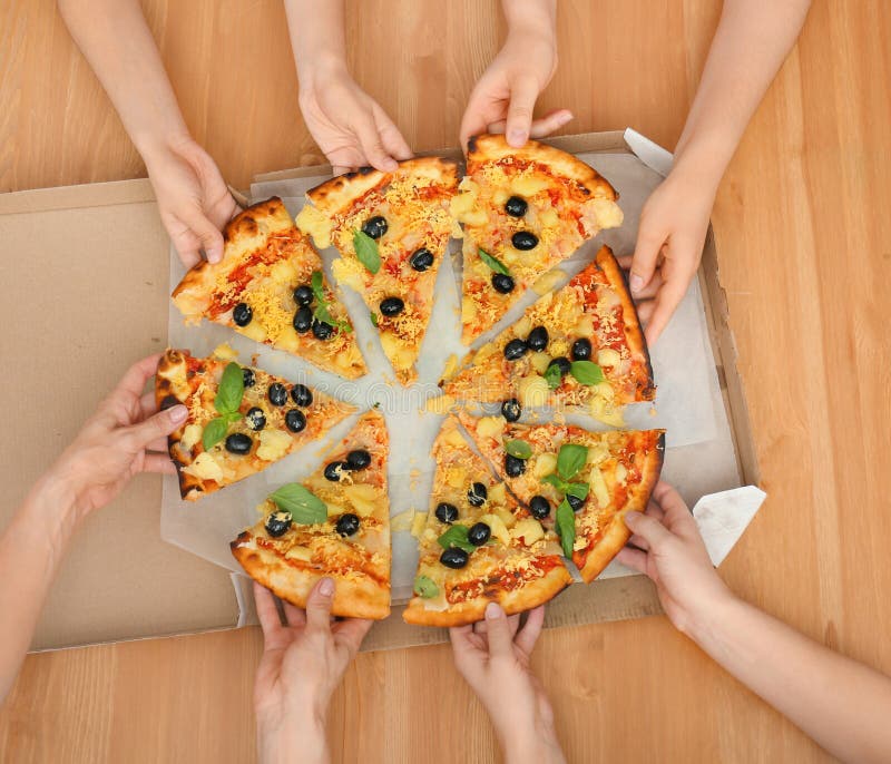 Women taking slices of tasty Italian pizza from box on wooden table, top view royalty free stock photo Women taking slices of tasty Italian pizza from box on wooden table, top view royalty free stock photo