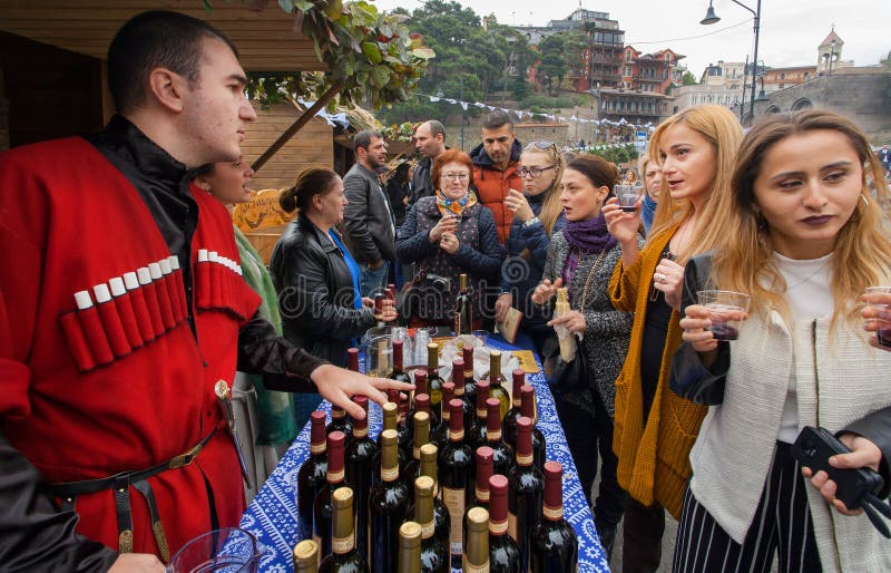 Women tasting wine with bartender in national georgian costume at festival