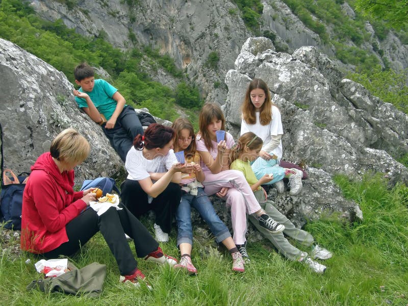 A group of women and children are resting and eating on the mountain. A group of women and children are resting and eating on the mountain