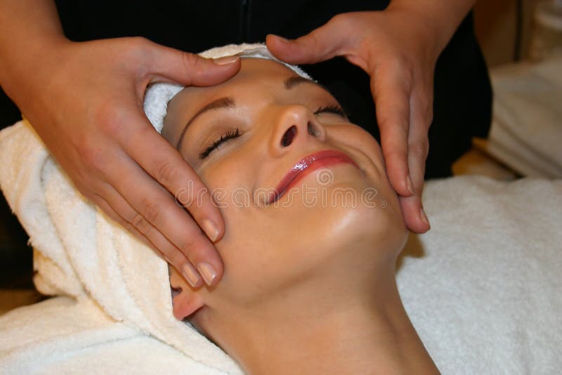 Woman smiles euphorically as she receives a facial massage. Woman smiles euphorically as she receives a facial massage.