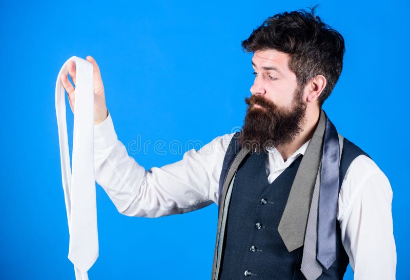 A wonderful necktie to a classic look. Brutal caucasian hipster holding necktie. Bearded man with necktie collection. Businessman choosing necktie for business suit.