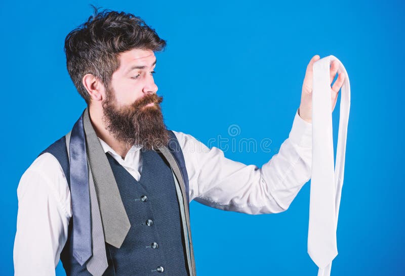 A wonderful necktie to a classic look. Brutal caucasian hipster holding necktie. Bearded man with necktie collection. Businessman choosing necktie for business suit.