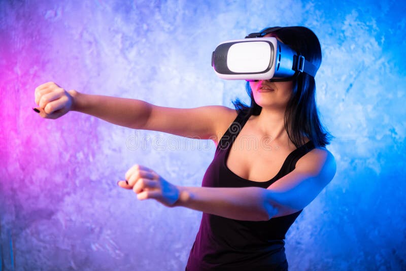 Wondering Young Woman in Virtual Reality Glasses over neon colored background. Shocked Girl wearing VR device. Close-up