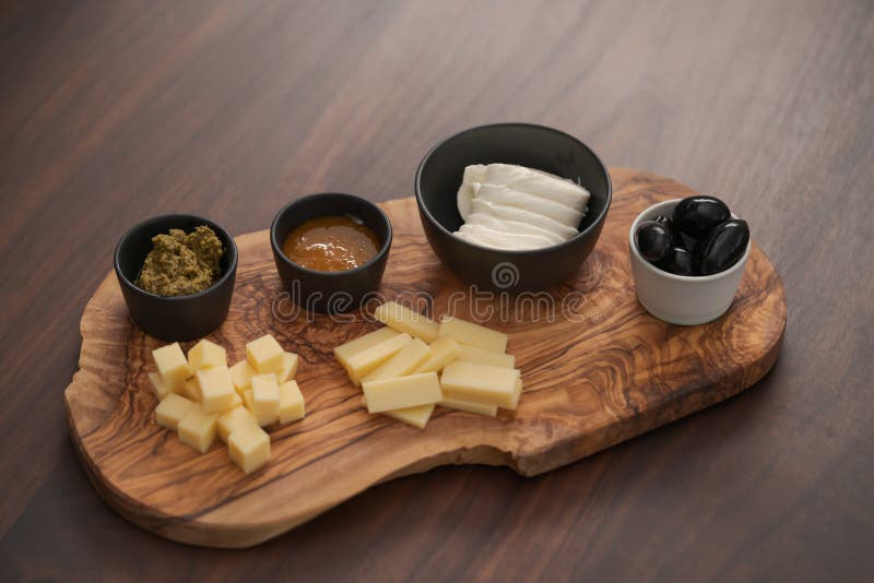 Wood Board with Cheese, Olives and Sauces on Walnut Table Stock Image