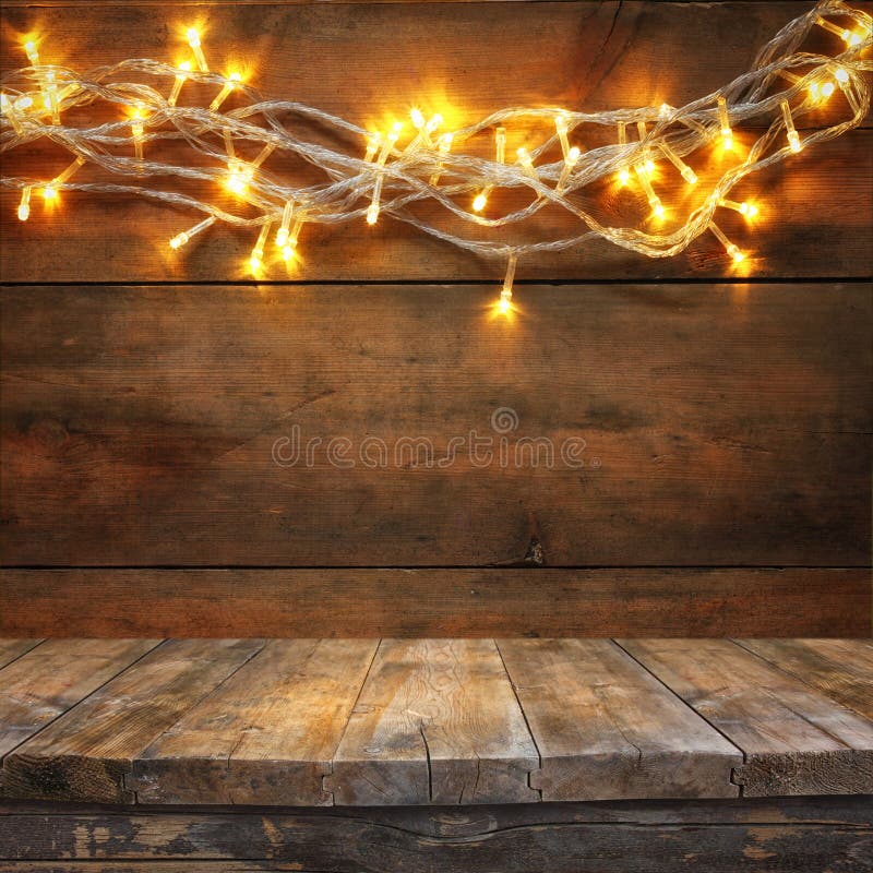 Drevená doska stola pred Vianocami teplé zlato garland svetlá na drevený rustikálny pozadí.