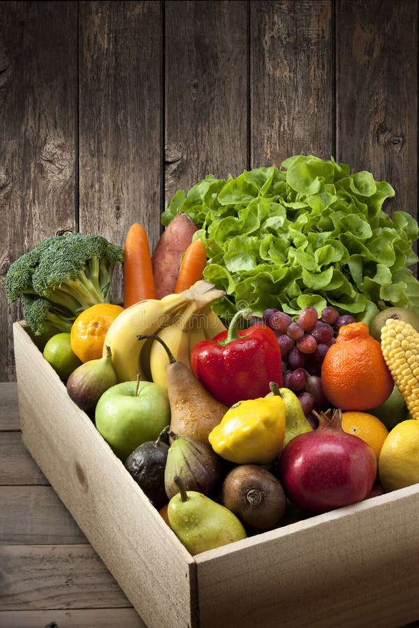 Mixed fresh fruit and vegetables in a wood crate and wood background. Mixed fresh fruit and vegetables in a wood crate and wood background