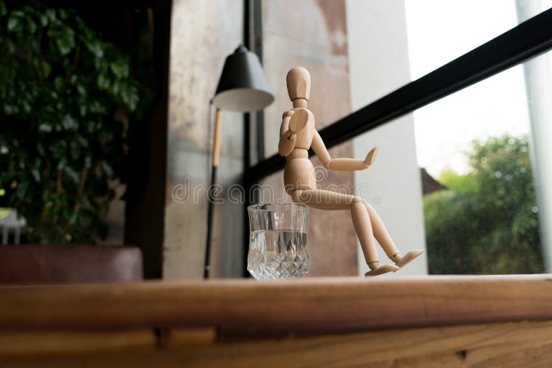 Wood man is sitting on a glass of water royalty free stock photography