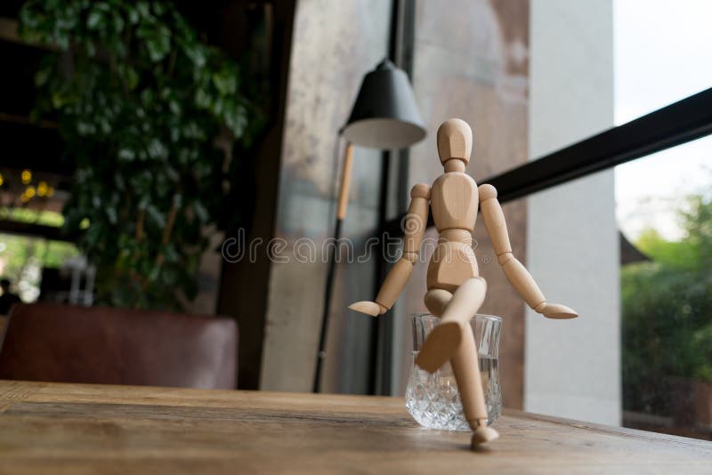 Wood man is sitting on a glass of water royalty free stock photo