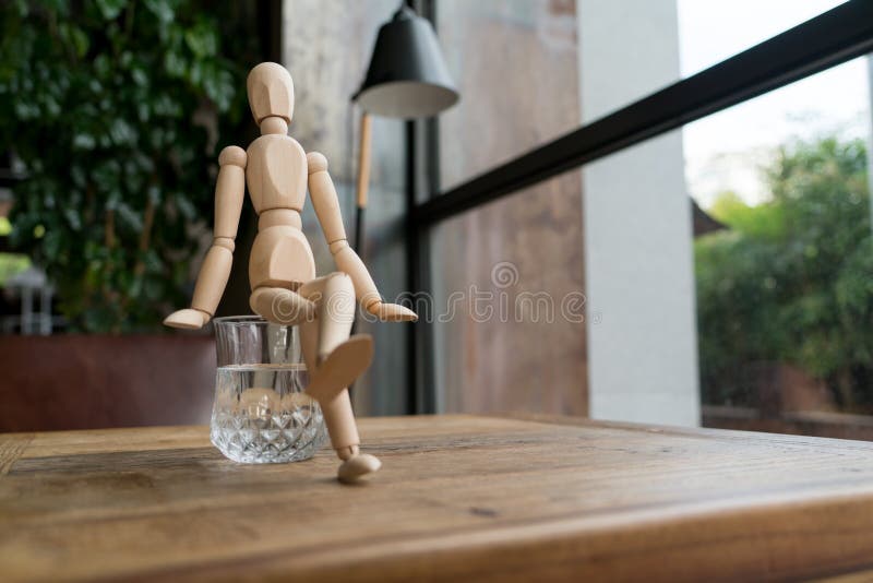 Wood man is sitting on a glass of water royalty free stock photos