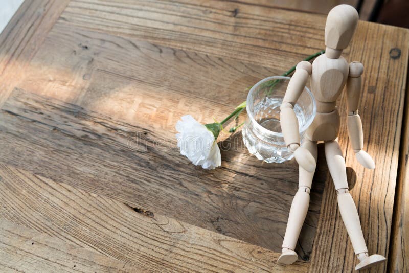 A wood man is sitting and put the arm on the glass of water stock photos