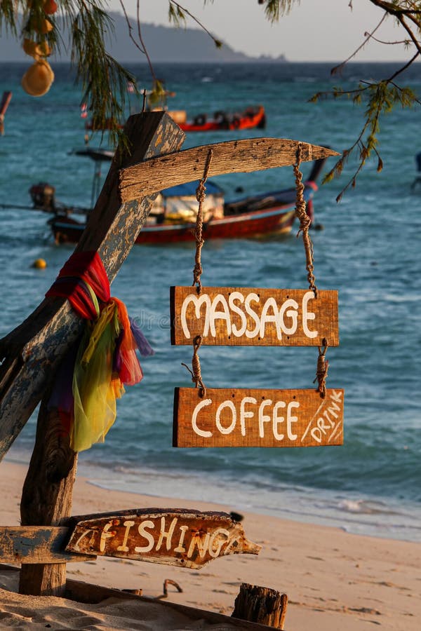 Wood sign of coffee, massage, fishing text at beautiful Thailand travel island Koh Lipe morning peace sea sand beach with sunrise