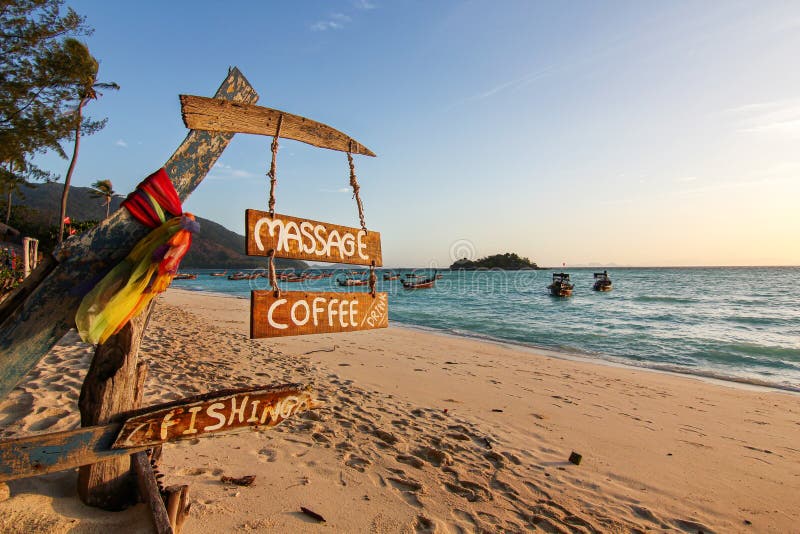 Wood sign of coffee, massage, fishing text at beautiful Thailand travel island Koh Lipe morning peace sea sand beach with sunrise