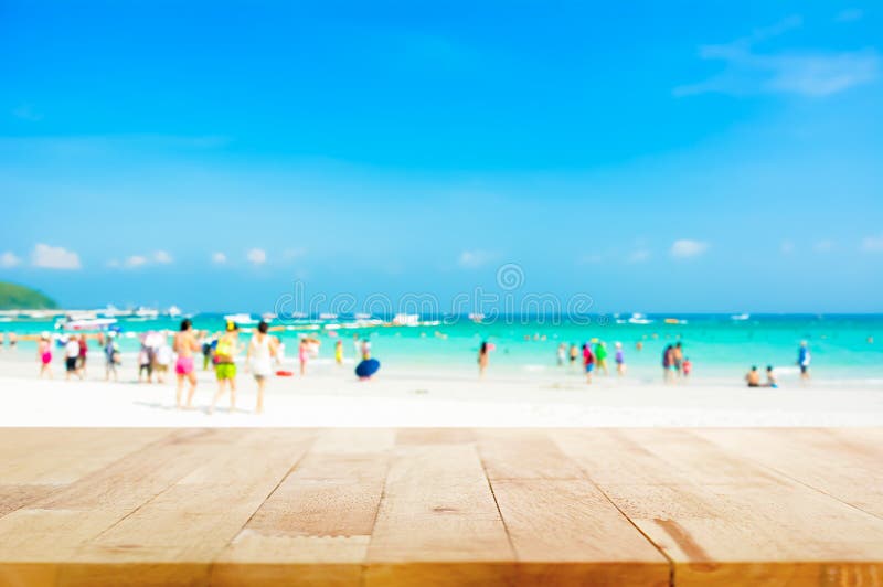 Wood table top on blurred beach background with people in colorful clothes stock photo Wood table top on blurred beach background with people in colorful clothes stock photo