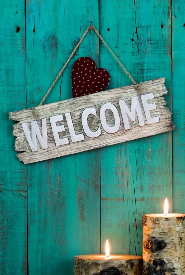Wood welcome sign with red heart by candlelight hanging on antique teal blue background