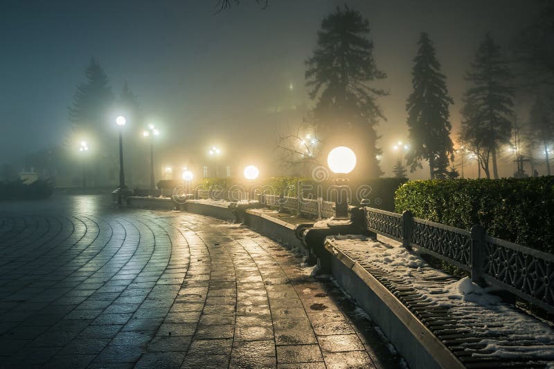Wooden Bench in the Snow in a Winter Night Park in the Fog. Footpath in a  Winter City Park at Night in Fog with Benches and Stock Photo - Image of  lamp,