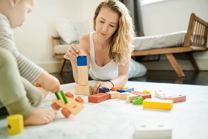 Wooden blocks, baby toys and mother playing with child in family home bedroom for fun. Woman or mom with toddler child royalty free stock image