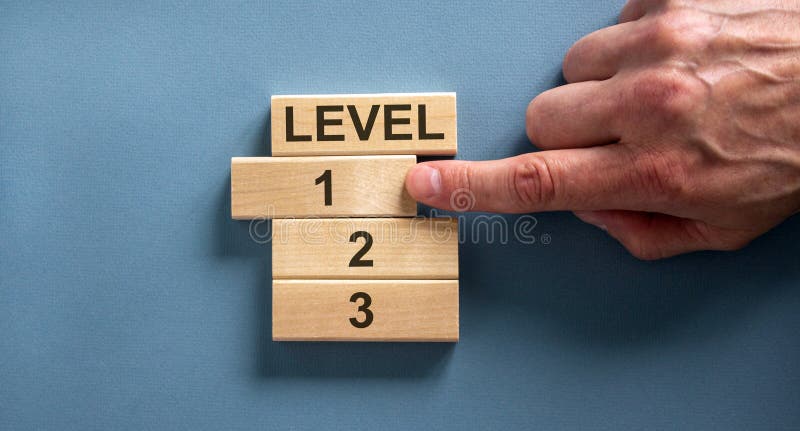 Wooden blocks form the words `level, 1, 2, 3,` on blue background. Male hand. Beautiful background. Business concept, copy space