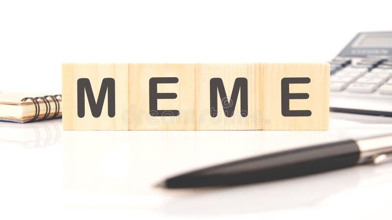 Wooden blocks spell out the word meme on a desk surrounded by a calculator and notebook, highlighting the intersection