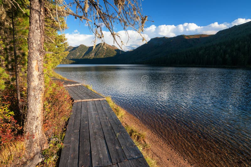 Wooden boardwalk along the lake in the mountains stock photos
