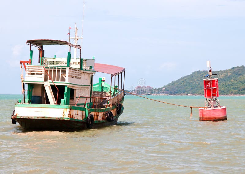 Wooden boat moored at red buoy