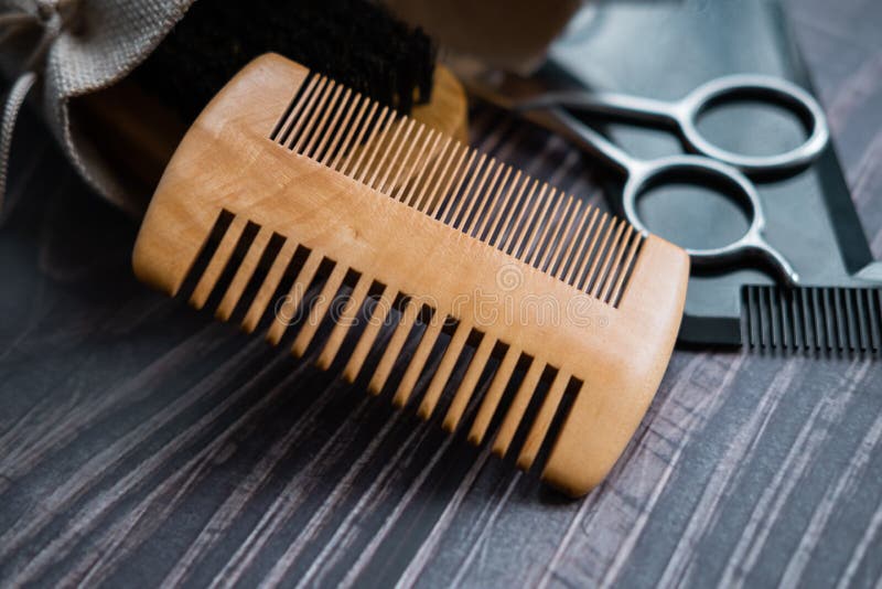 Wooden comb and other tools for beard trimming in background. Close up view