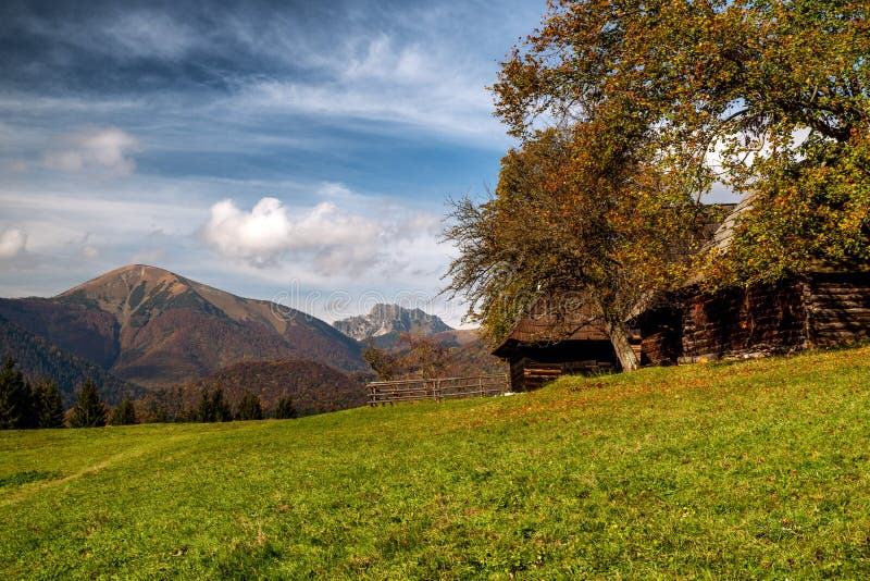 Drevená chata na lúke a hory v pozadí. Obec Podšíp na Slovensku
