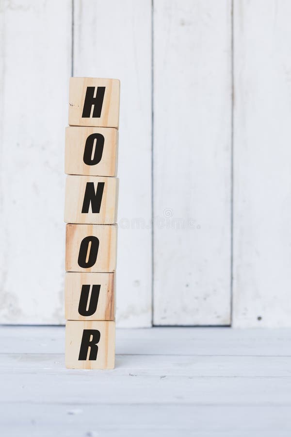 wooden cube, with the word honour, with white wooden background stock image