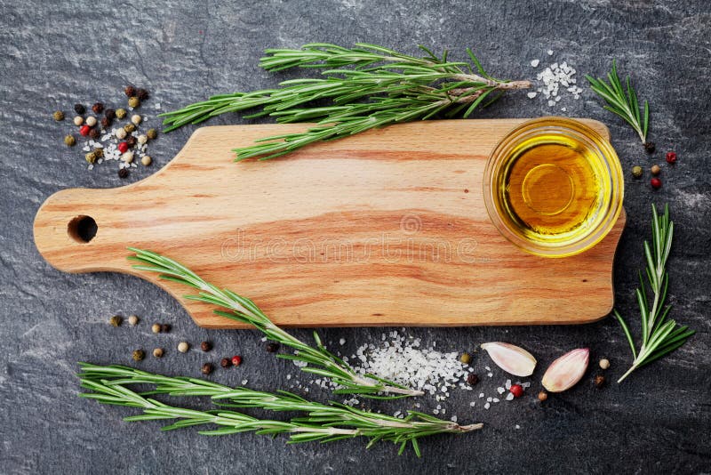 Wooden cutting board, olive oil, rosemary plant, salt, garlic and pepper on black table from above for food cooking background or royalty free stock photos Wooden cutting board, olive oil, rosemary plant, salt, garlic and pepper on black table from above for food cooking background or royalty free stock photos