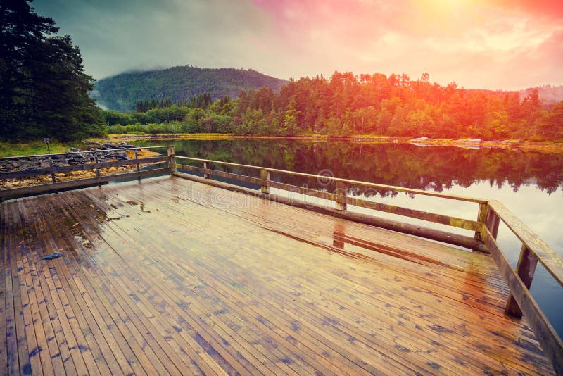 Wooden deck on a lakeshore. Rocky shore of the mountain lake