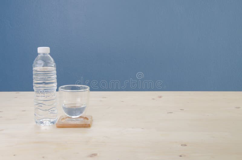 Wooden Desk with Drinking Water in Glass and Blue Cement Background