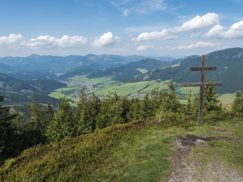 wooden double cross with view on village Liptovska Luzna at ridge of Low Tatras mountains with mountains, hills, meadow