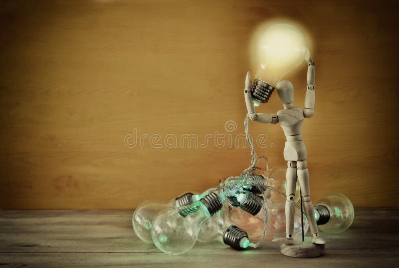 Wooden Dummy Holding Shiny Light Bulb. New Idea Concept Stock Image
