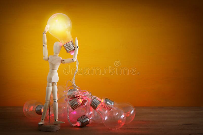 Wooden Dummy Holding Shiny Light Bulb. New Idea Concept Stock Image