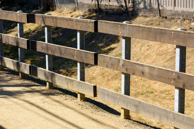 Wooden fence along a dirt path, with metal posts supporting the wooden panels stock photo