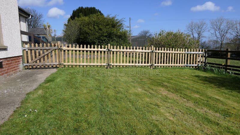 Wooden fence and gate for children on garden lawn