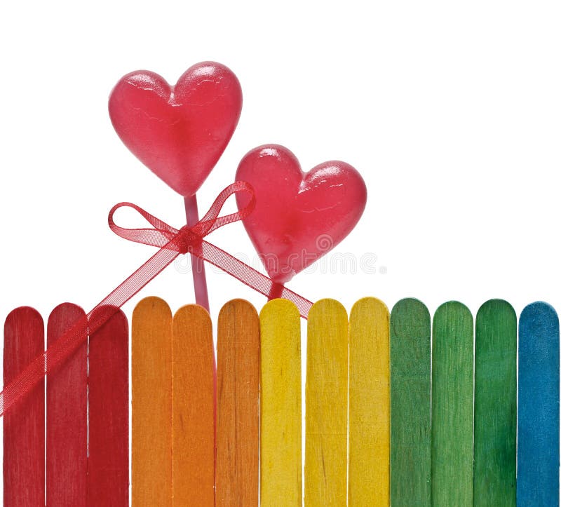 Wooden fence in rainbow colors and two lollipops in heart shape stock photography Wooden fence in rainbow colors and two lollipops in heart shape stock photography