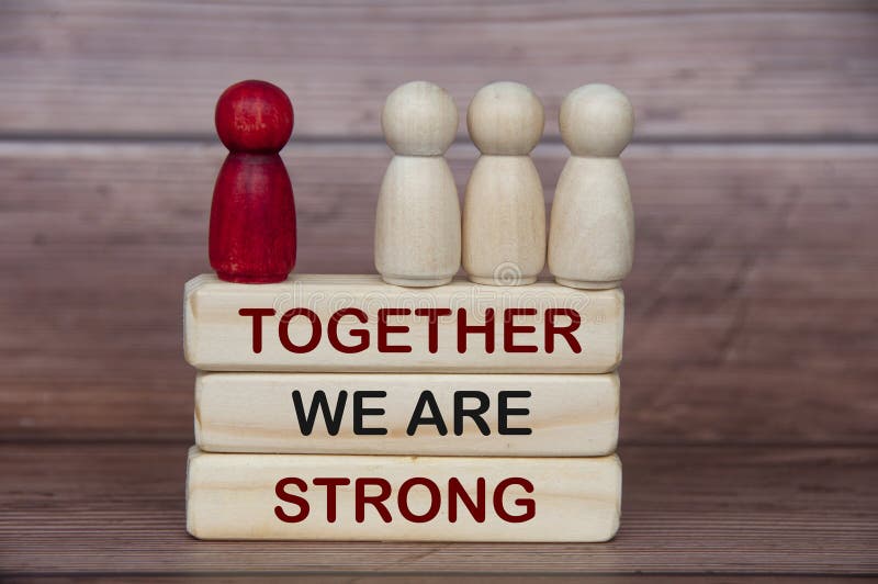 Wooden figure dolls on top of wooden blocks with text - Together we are strong.