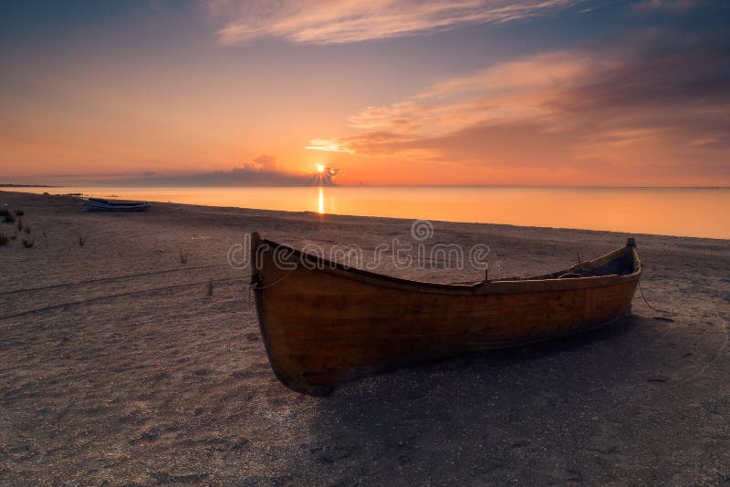 Wooden fishing boat resting on the beach at sunrise