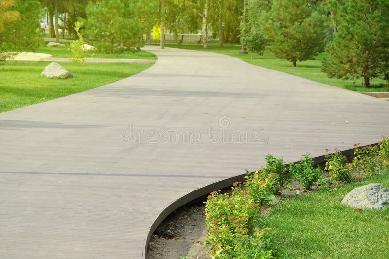 Wooden flooring - a beautiful promenade walkway for walks in the city Park on a background of green grass and trees on a Sunny stock images Wooden flooring - a beautiful promenade walkway for walks in the city Park on a background of green grass and trees on a Sunny stock images