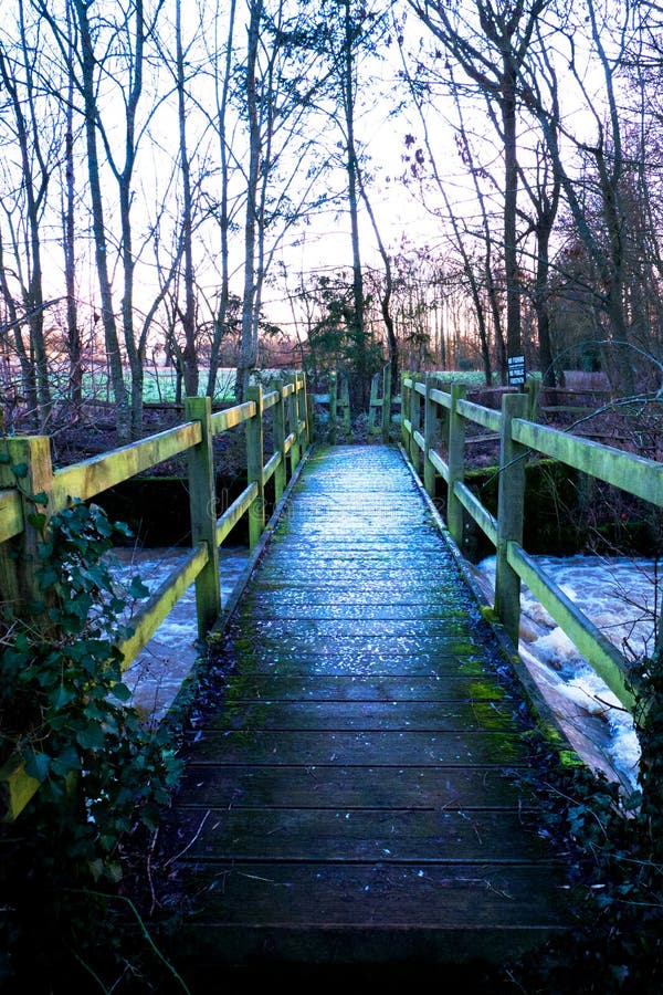 Wooden foot bridge in a wood over a river, a layer of snow on th royalty free stock photography Wooden foot bridge in a wood over a river, a layer of snow on th royalty free stock photography