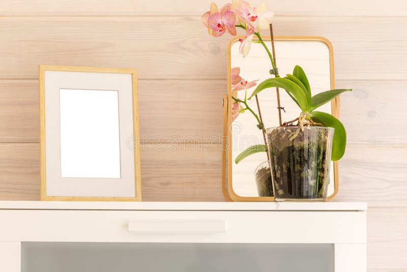 Wooden frame mock up and phalaenopsis orchid on a white chest in a bedroom of a wooden house with white trim. stock photography Wooden frame mock up and phalaenopsis orchid on a white chest in a bedroom of a wooden house with white trim. stock photography