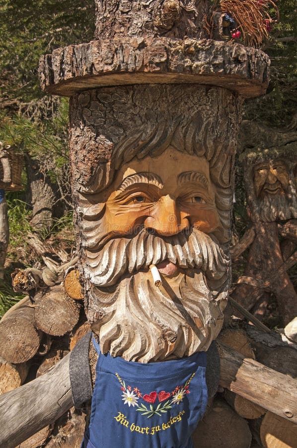 Wooden Gnome Near Wooden Fence on Ground. Old Cracked Figure Carved