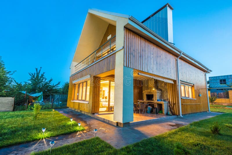 Wooden house with meadow in front of it. Beautiful wooden house with a lawn. Facade of traditional homes with grass in the foreground. at sunset and sunrise royalty free stock images Wooden house with meadow in front of it. Beautiful wooden house with a lawn. Facade of traditional homes with grass in the foreground. at sunset and sunrise royalty free stock images