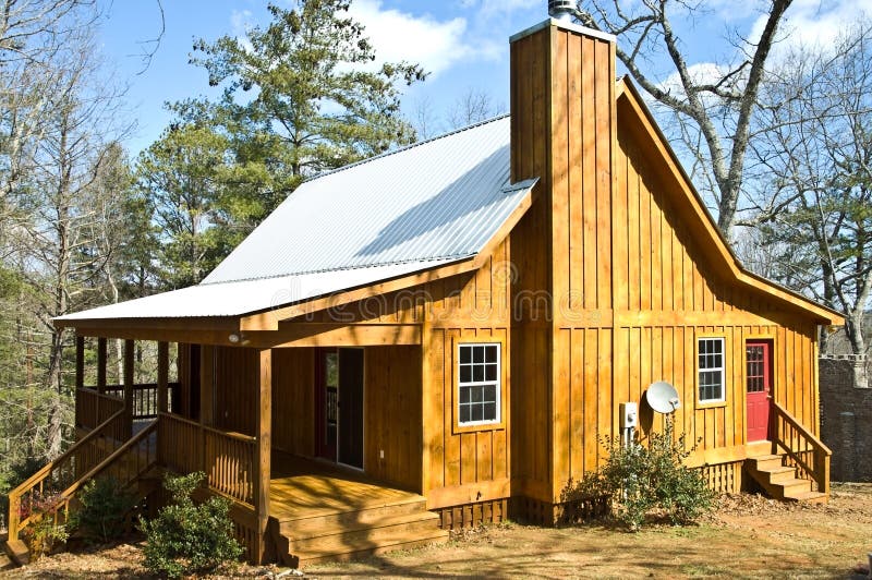 A small wood house with a tin roof, view of the front and side with a bright red door. A small wood house with a tin roof, view of the front and side with a bright red door.