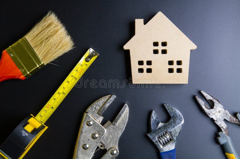 Wooden house toy and construction tools on black background with copy space.Real estate concept, New house concept, Finance loan business concept, Repair maintenance concept