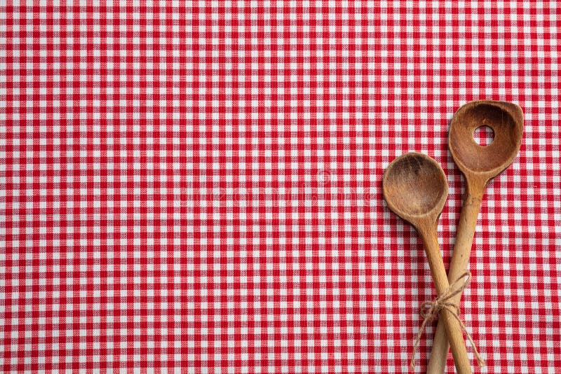 Wooden kitchen utensils on red checkered picnic tablecloth, top view, copy space