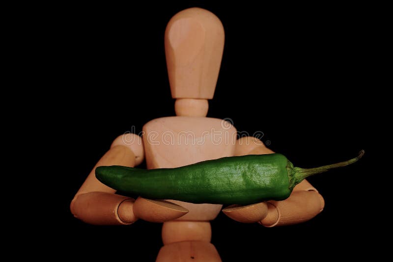 Wooden manikin with a pepper in her arms royalty free stock photo Wooden manikin with a pepper in her arms royalty free stock photo