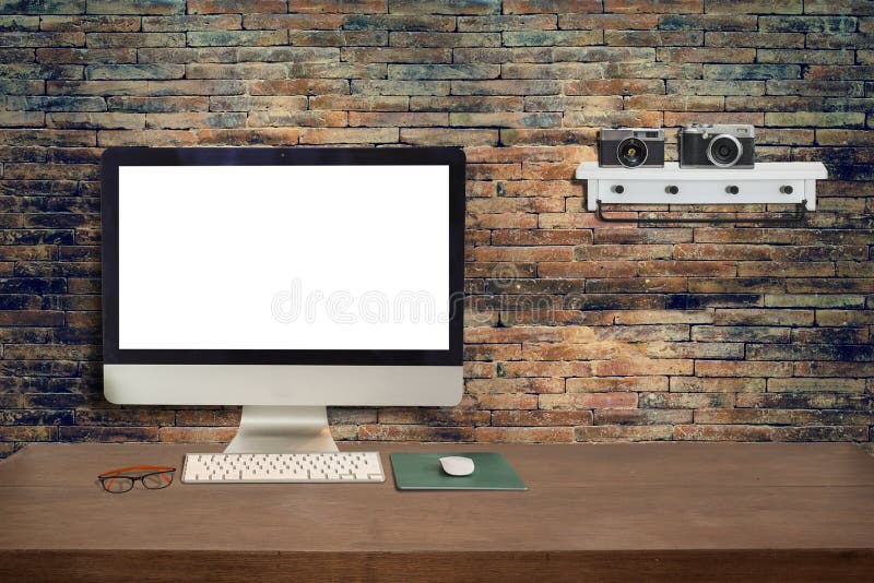 Wooden Office Desk And Blank Monitor With Old Brick Wall Stock