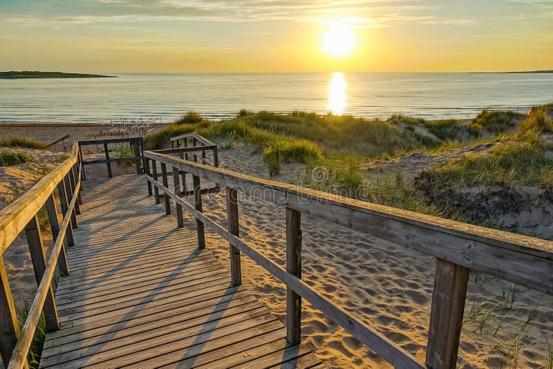 Wooden path at Baltic sea over sand dunes with ocean view, sunset summer evening