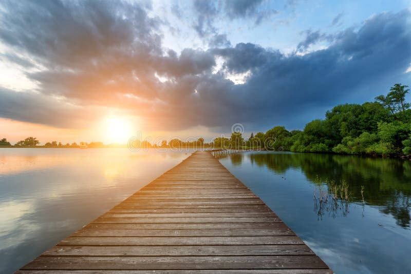 Wooden Path Bridge Over Lake At Stormy Dramatic Sunset Stock Image